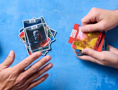 Close up of peoples hands as they deal Disney Worlds of Wonder cards.